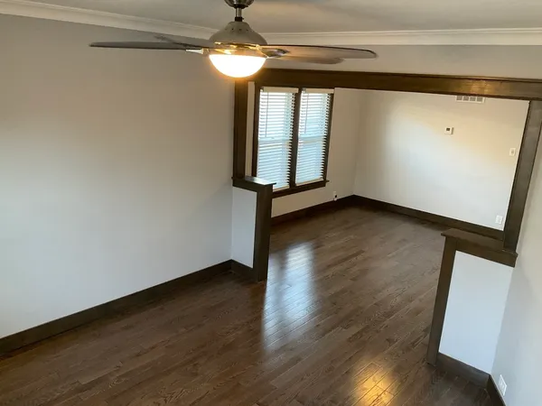 a view of empty room with wooden floor and fan