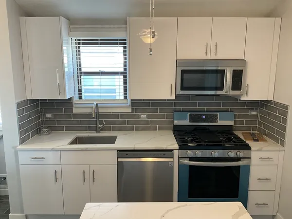 a kitchen with stainless steel appliances granite countertop a sink stove microwave and refrigerator