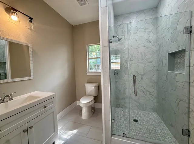 a bathroom with a granite countertop sink toilet a mirror and shower