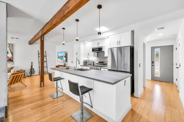 a kitchen with stainless steel appliances granite countertop a sink a stove a refrigerator and island with wooden floor