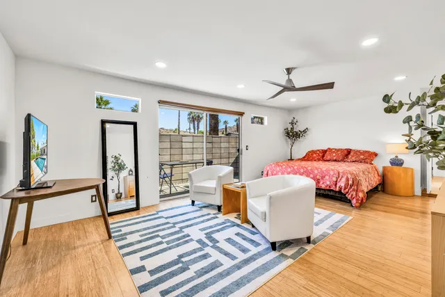 a bedroom with a bed wooden floor and large window