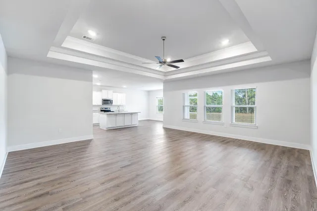 a view of an empty room with window and wooden floor