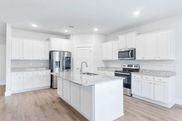 a kitchen with a sink a counter top space stainless steel appliances and cabinets