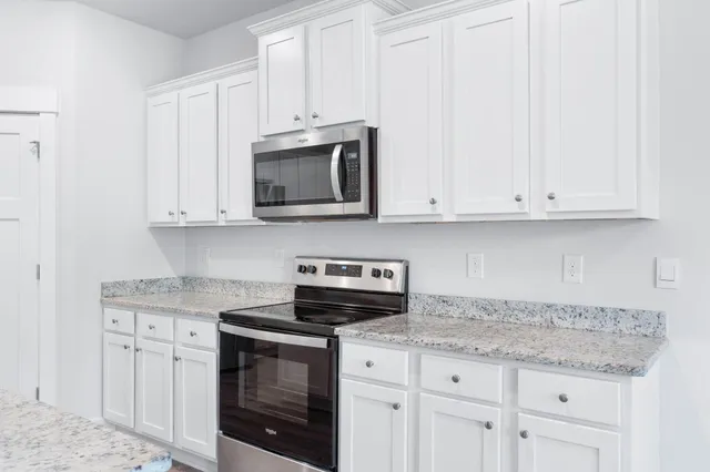 a kitchen with granite countertop white cabinets stainless steel appliances and a sink