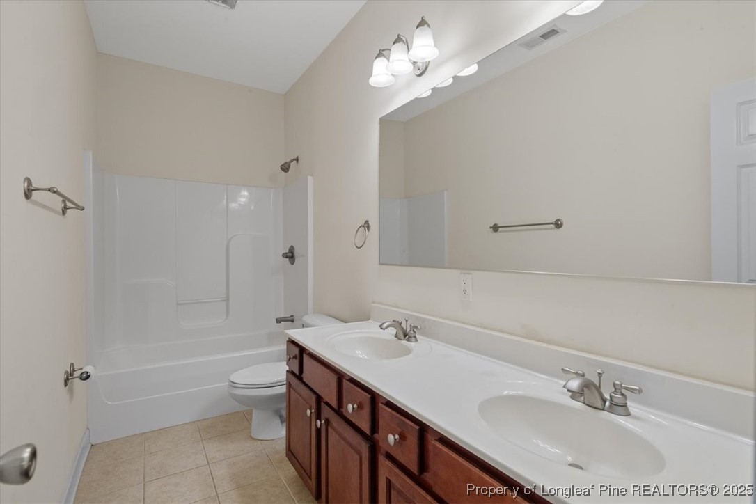 930 Westland Ridge Road Fayetteville, NC 28311 - Photo 38 of 50 a bathroom with a double vanity sink a toilet a mirror and shower