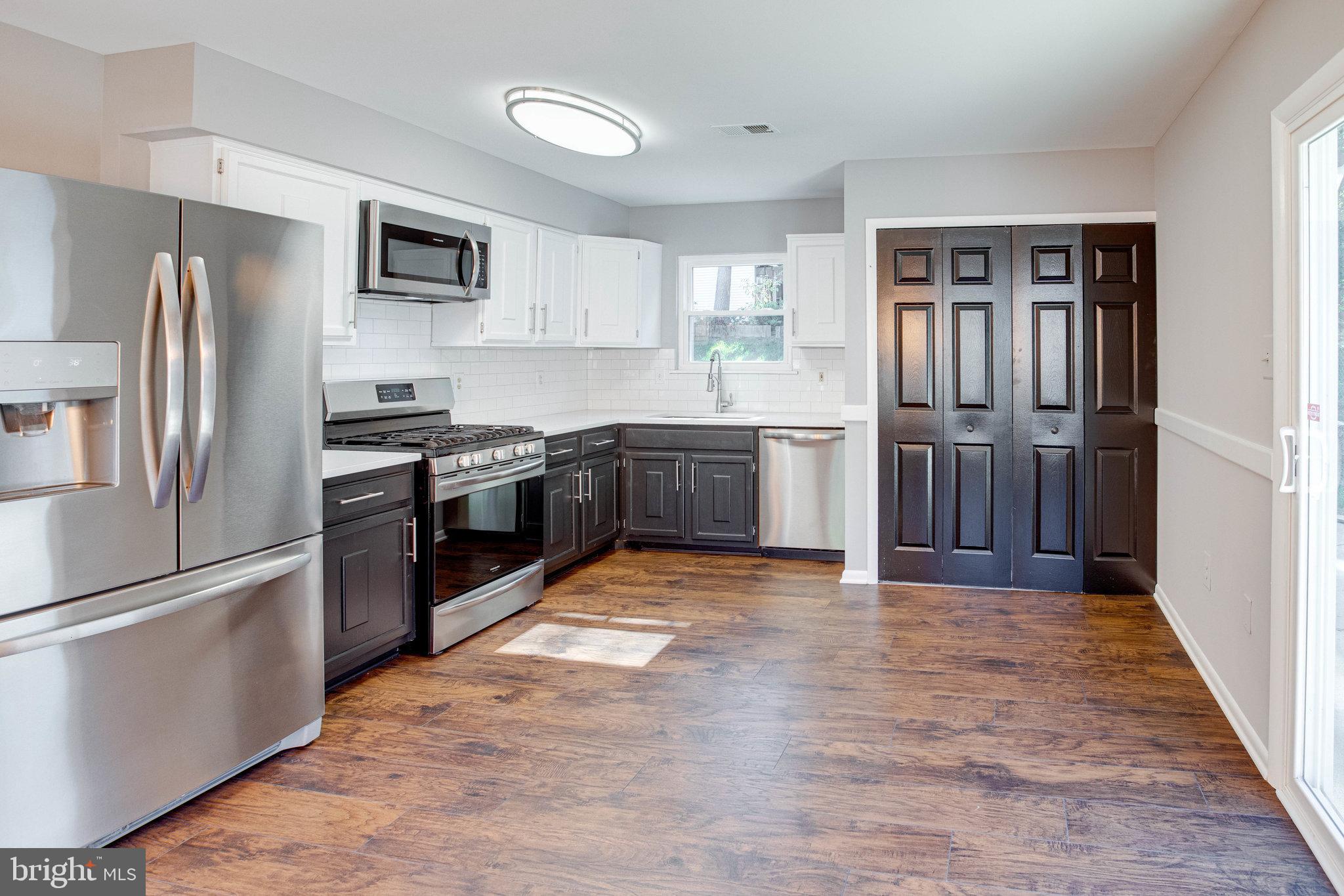a large kitchen with stainless steel appliances granite countertop a refrigerator stove and sink