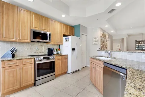 a kitchen with granite countertop a sink stainless steel appliances and cabinets