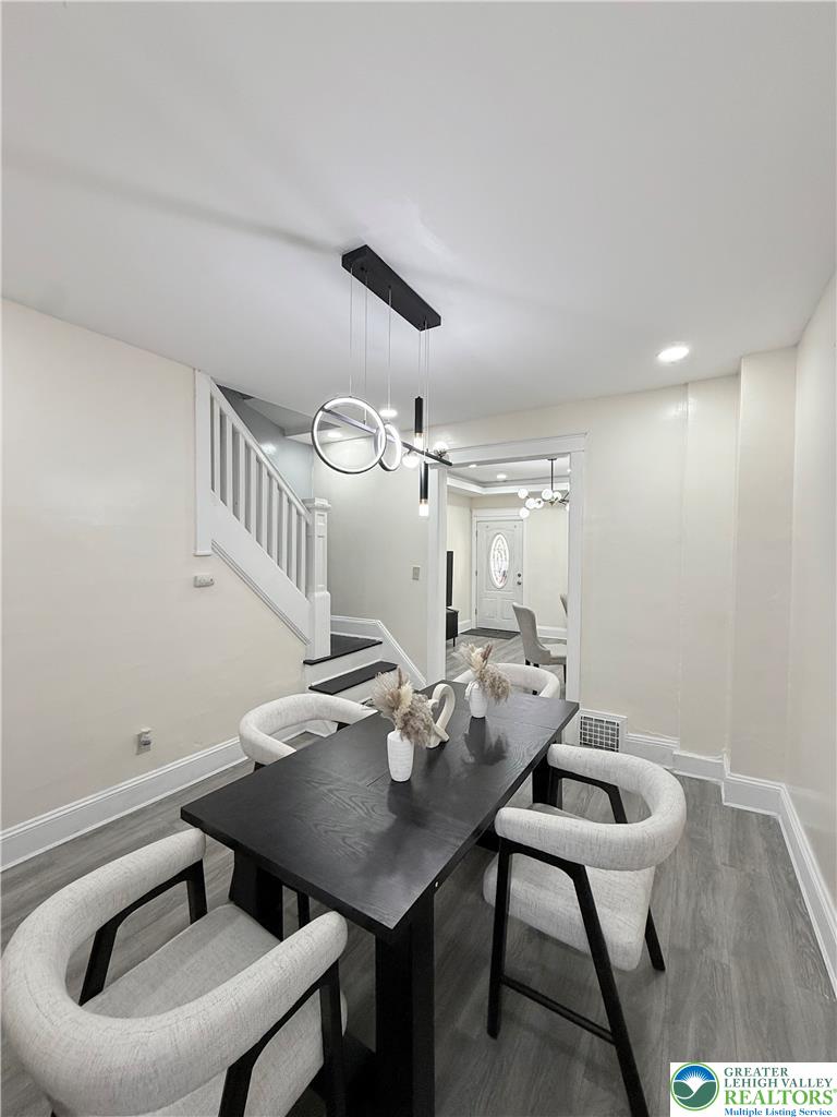 1025 Spring Street Bethlehem, PA 18018 - Photo 5 of 20 A contemporary chandelier illuminates the dining area, featuring sleek flooring and an elegant staircase.