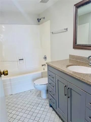 a bathroom with a granite countertop sink a toilet and bathtub