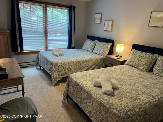 a bedroom with two beds and large windows