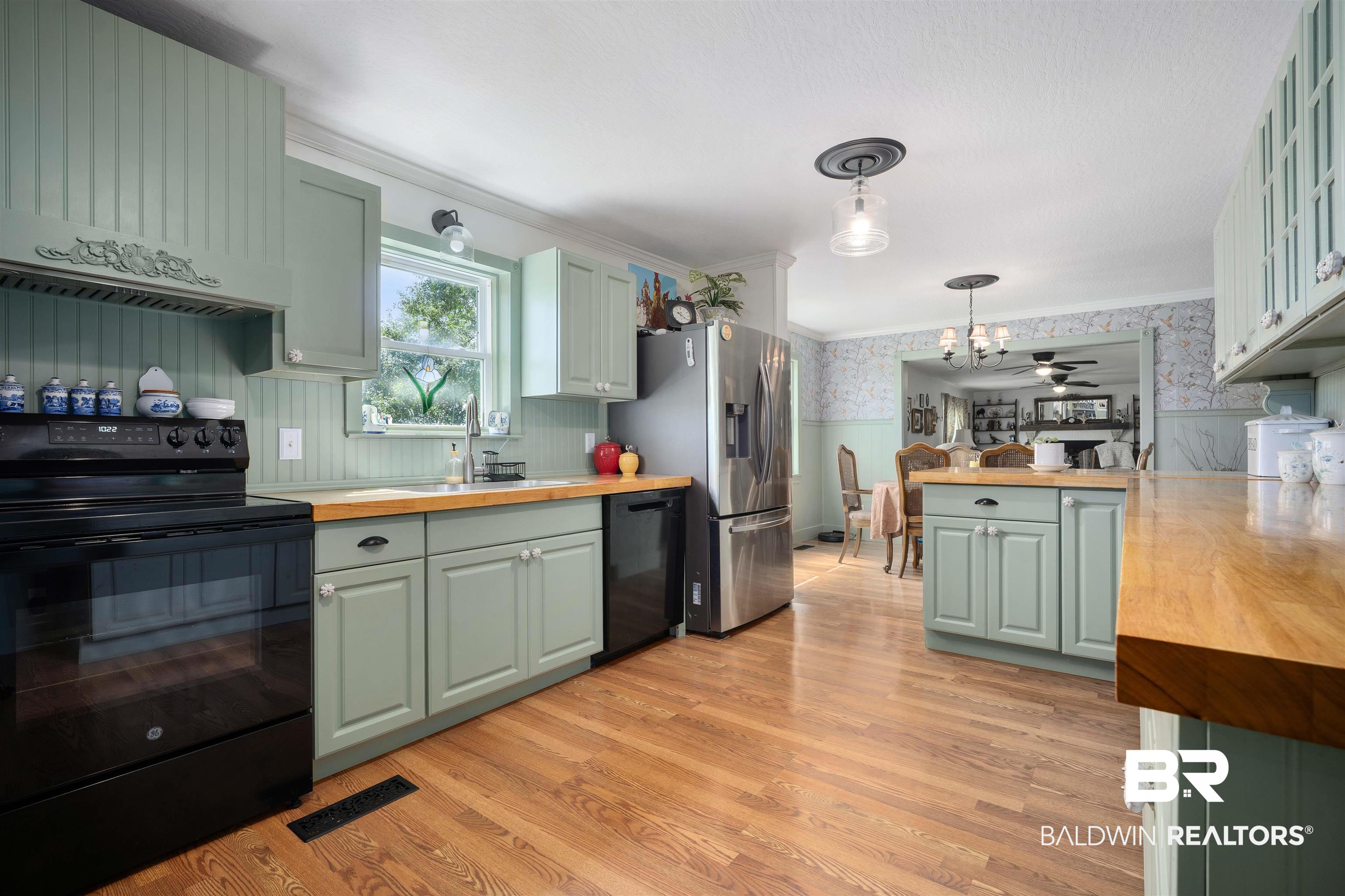 22 Horace Odom Road Millry, AL 36558 - Photo 10 of 39 Kitchen with wallpapered walls, black appliances, a wainscoted wall, butcher block countertops, and light wood finished floors
