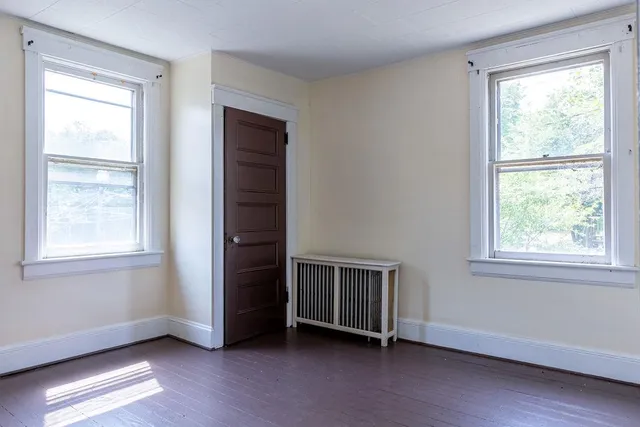 a view of an empty room with a window and wooden floor