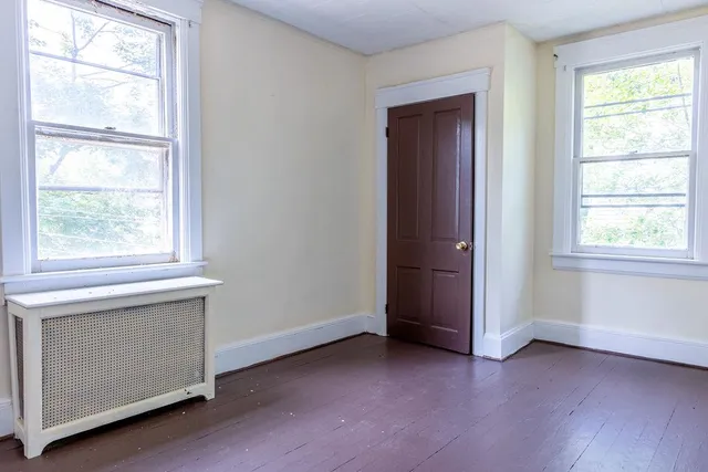 a view of empty room with window and wooden floor