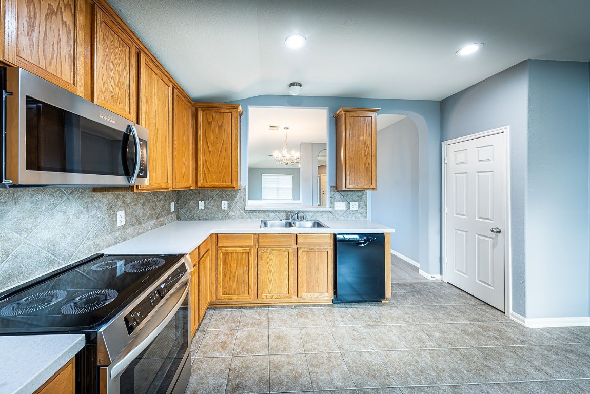 22715 Imperial Ivy Court Spring, TX 77373 - Photo 35 of 45 a kitchen with granite countertop a stove a sink and a microwave