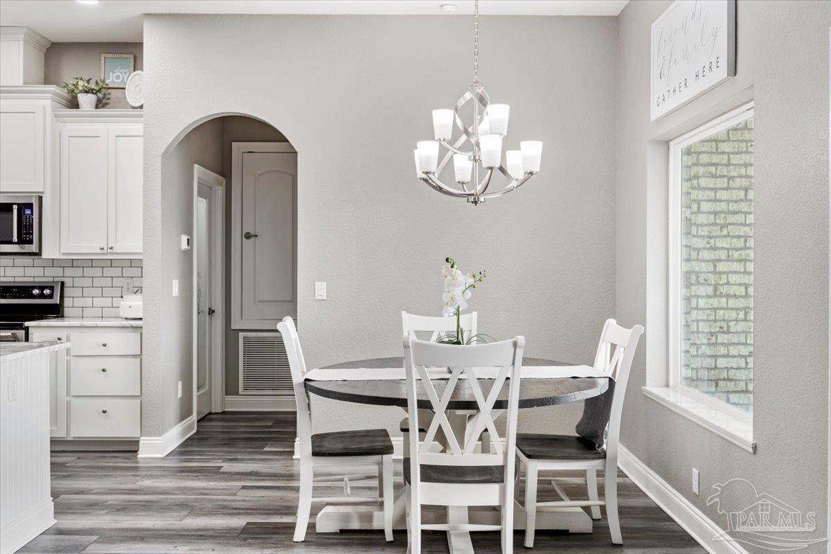 9258 Roy Cook Road Pace, FL 32571 - Photo 28 of 63 a view of a dining room with furniture a chandelier and wooden floor