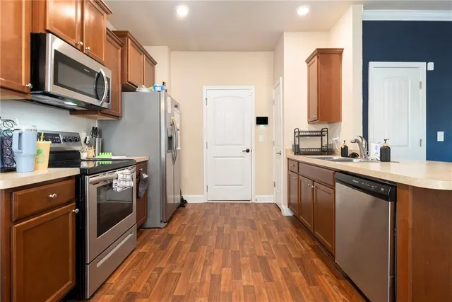 a kitchen with stainless steel appliances a stove a sink dishwasher a refrigerator and a microwave oven with wooden floor