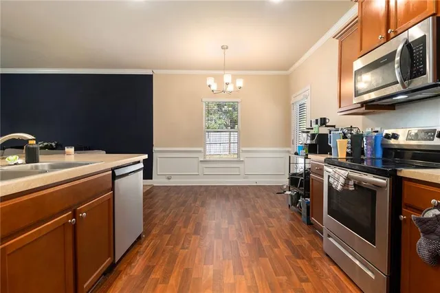 a kitchen with stainless steel appliances a stove a sink dishwasher and a microwave oven with wooden floor