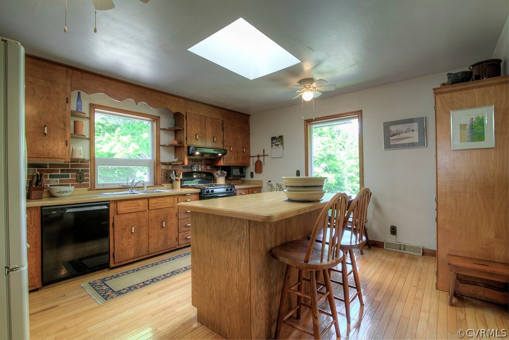 988 Manteo Road Buckingham, VA 23921 - Photo 6 of 24 a kitchen with stainless steel appliances granite countertop a stove a refrigerator a sink dishwasher a dining table and chairs with wooden floor