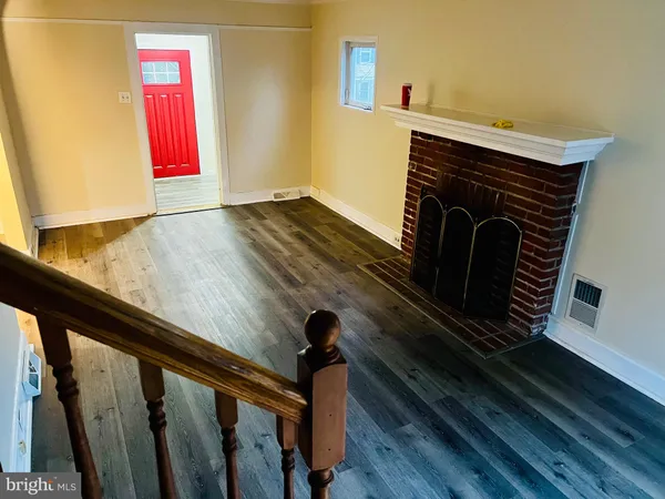 a view of an empty room with wooden floor and stairs