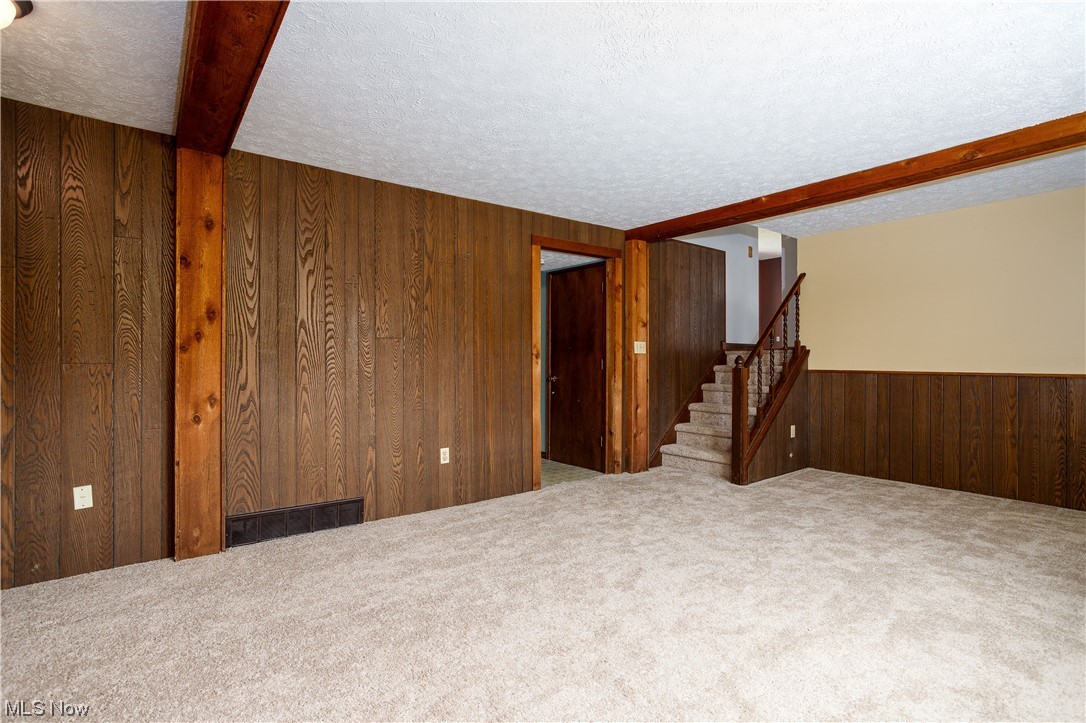 5680 Lance Road Medina, OH 44256 - Photo 19 of 32 Carpeted empty room with wood walls, a textured ceiling, and beamed ceiling