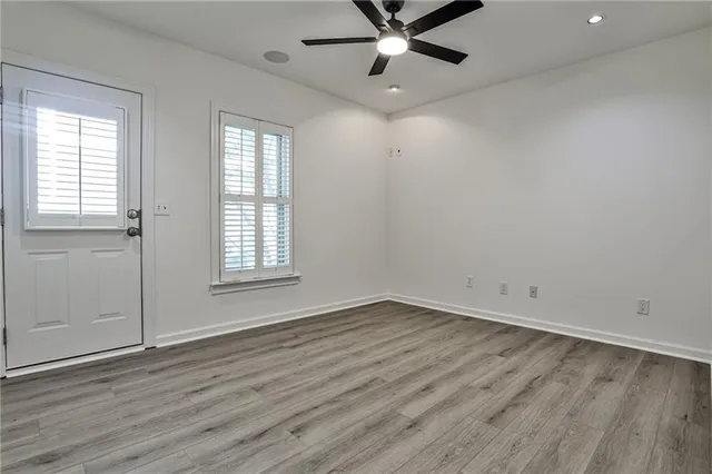 an empty room with wooden floor fan and windows
