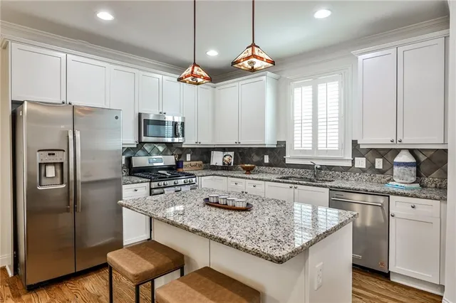 a kitchen with kitchen island granite countertop stainless steel appliances a sink stove a refrigerator a center island and cabinets