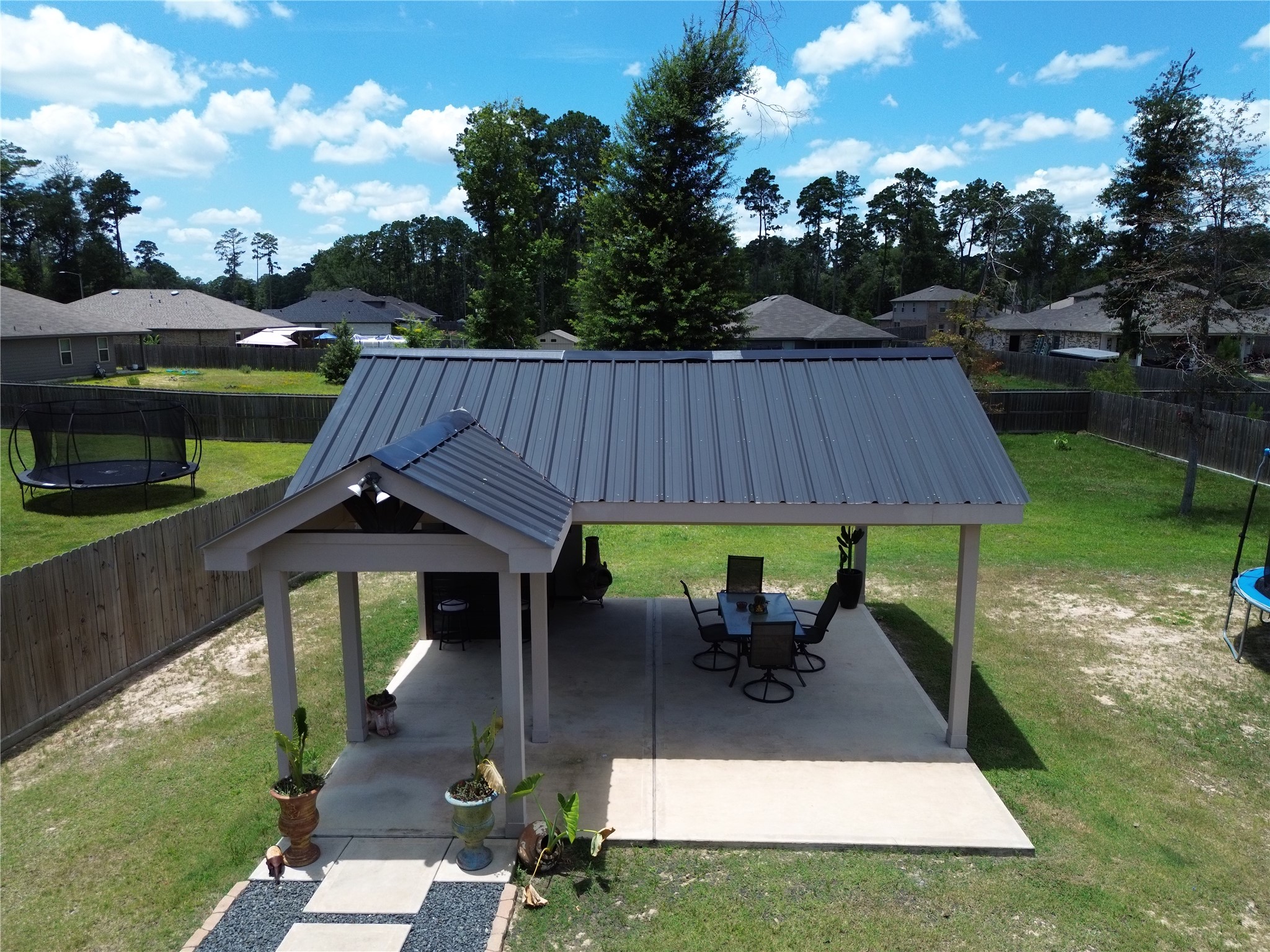 811 Republic Road New Caney, TX 77357 - Photo 2 of 41 Charming backyard pavilion with a sleek metal roof, perfect for outdoor dining and relaxation, set in a spacious fenced yard with lush greenery.