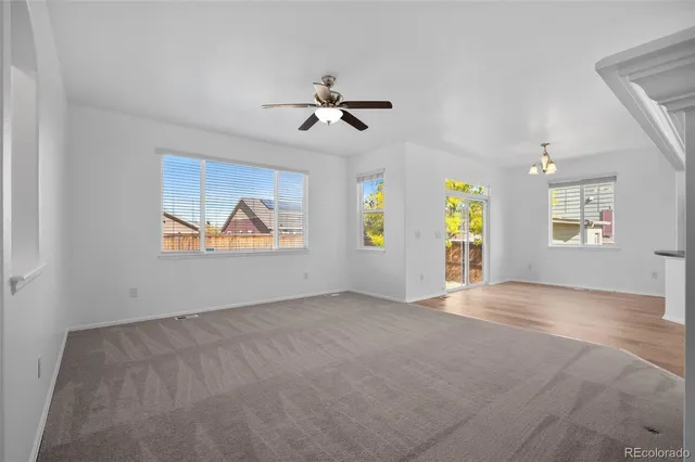 an empty room with windows and chandelier fan
