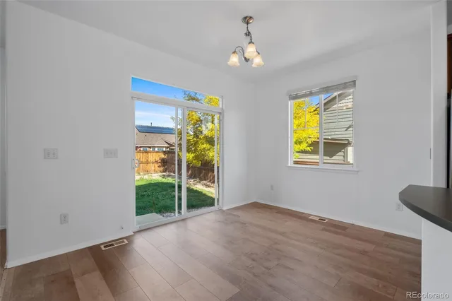a view of empty room with window and wooden floor