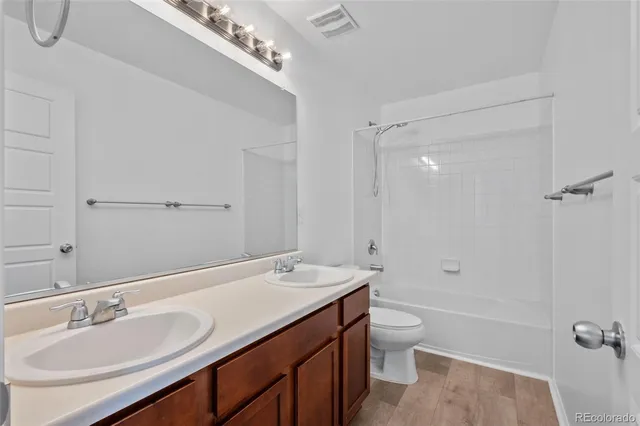 a bathroom with a granite countertop sink a toilet a shower and a mirror