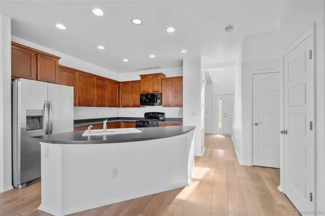 a kitchen with stainless steel appliances granite countertop a refrigerator a sink and a stove with wooden floor