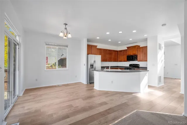 a view of kitchen with kitchen island stainless steel appliances wooden floor cabinets and a window