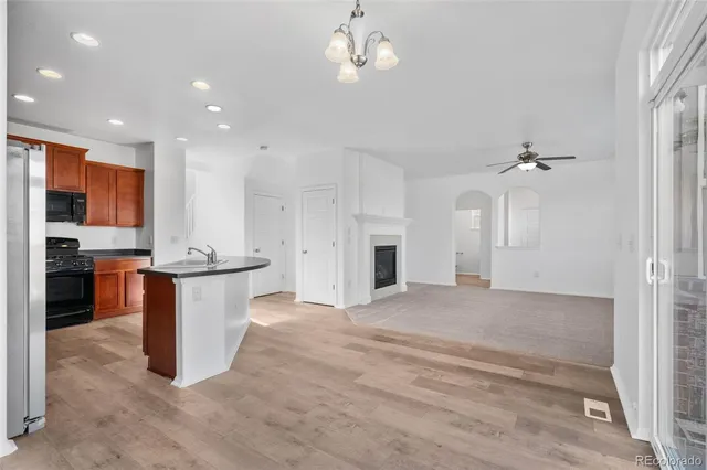 a large kitchen with kitchen island a stove a sink a refrigerator and white cabinets with wooden floor