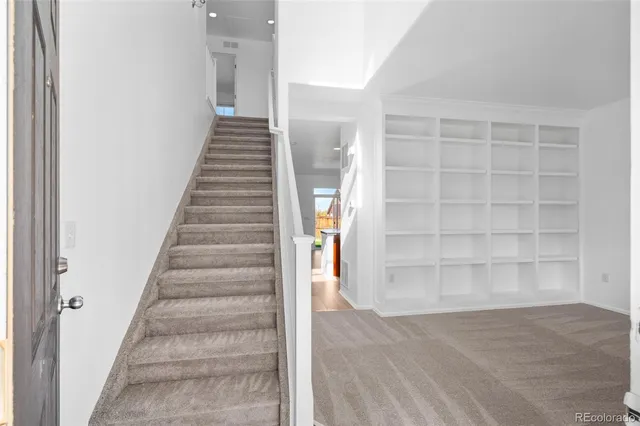a view of an empty room with stairs and a window