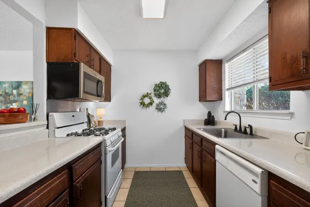 a kitchen with stainless steel appliances a sink a stove a microwave a sink a refrigerator and cabinets