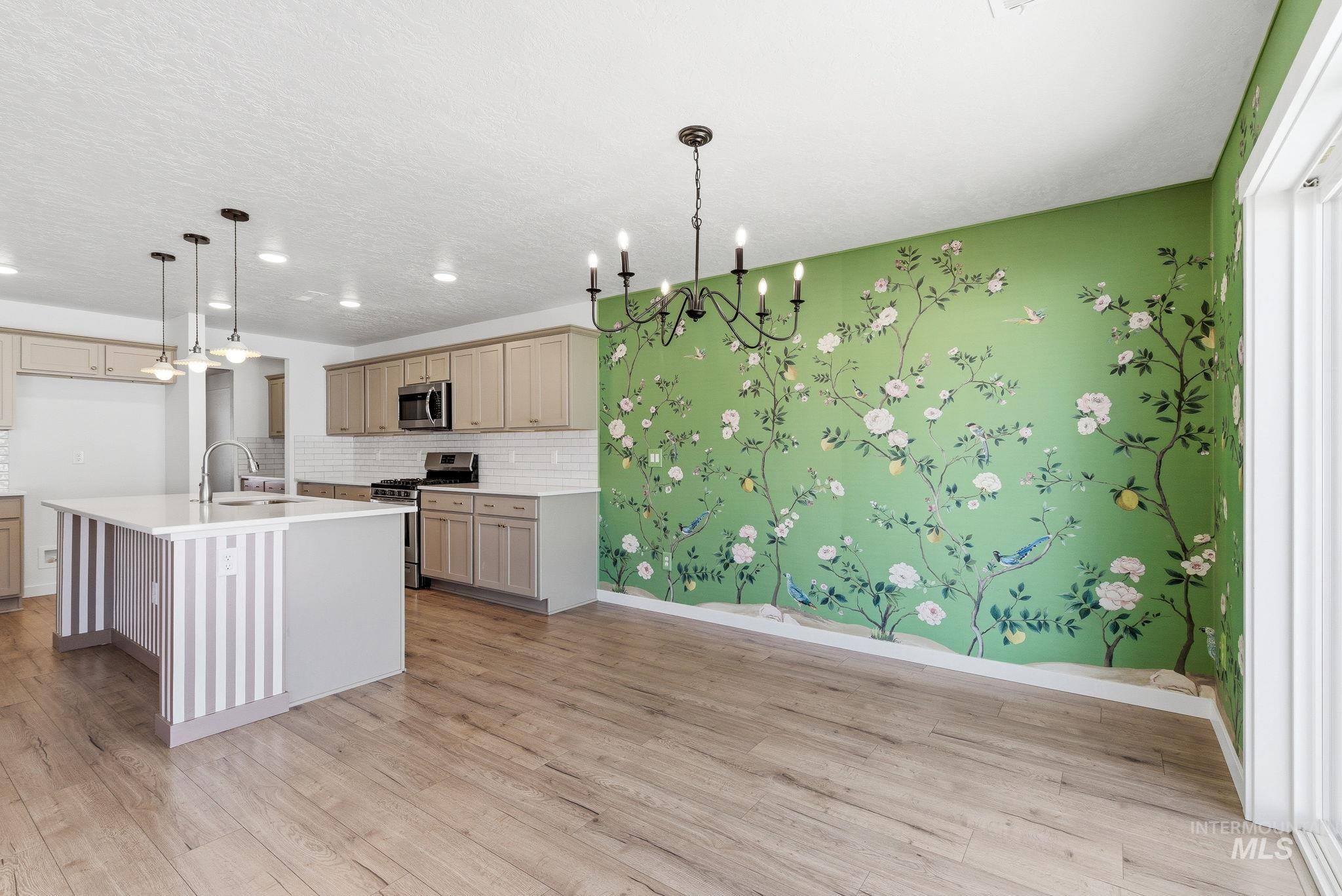 110 Homesteaders Street Middleton, ID 83644 - Photo 12 of 49 Kitchen with stainless steel appliances, hanging lights, light wood-style flooring, an island with sink, and decorative backsplash