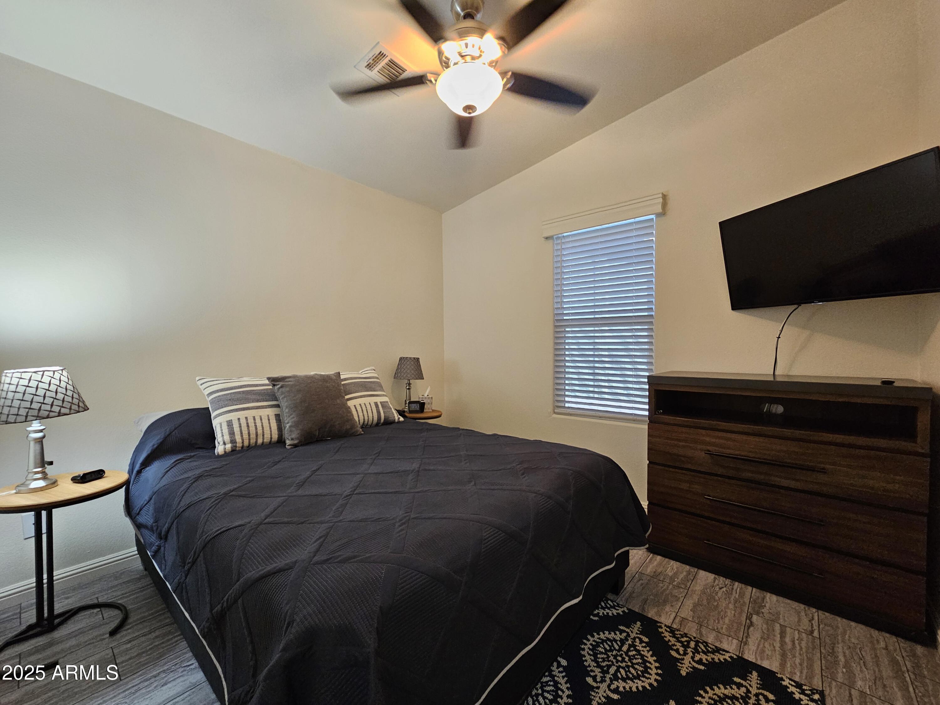 650 North Hawes Road, Unit 3124 Mesa, AZ 85207 - Photo 22 of 45 a bedroom with a bed a flat screen tv and a bookshelf