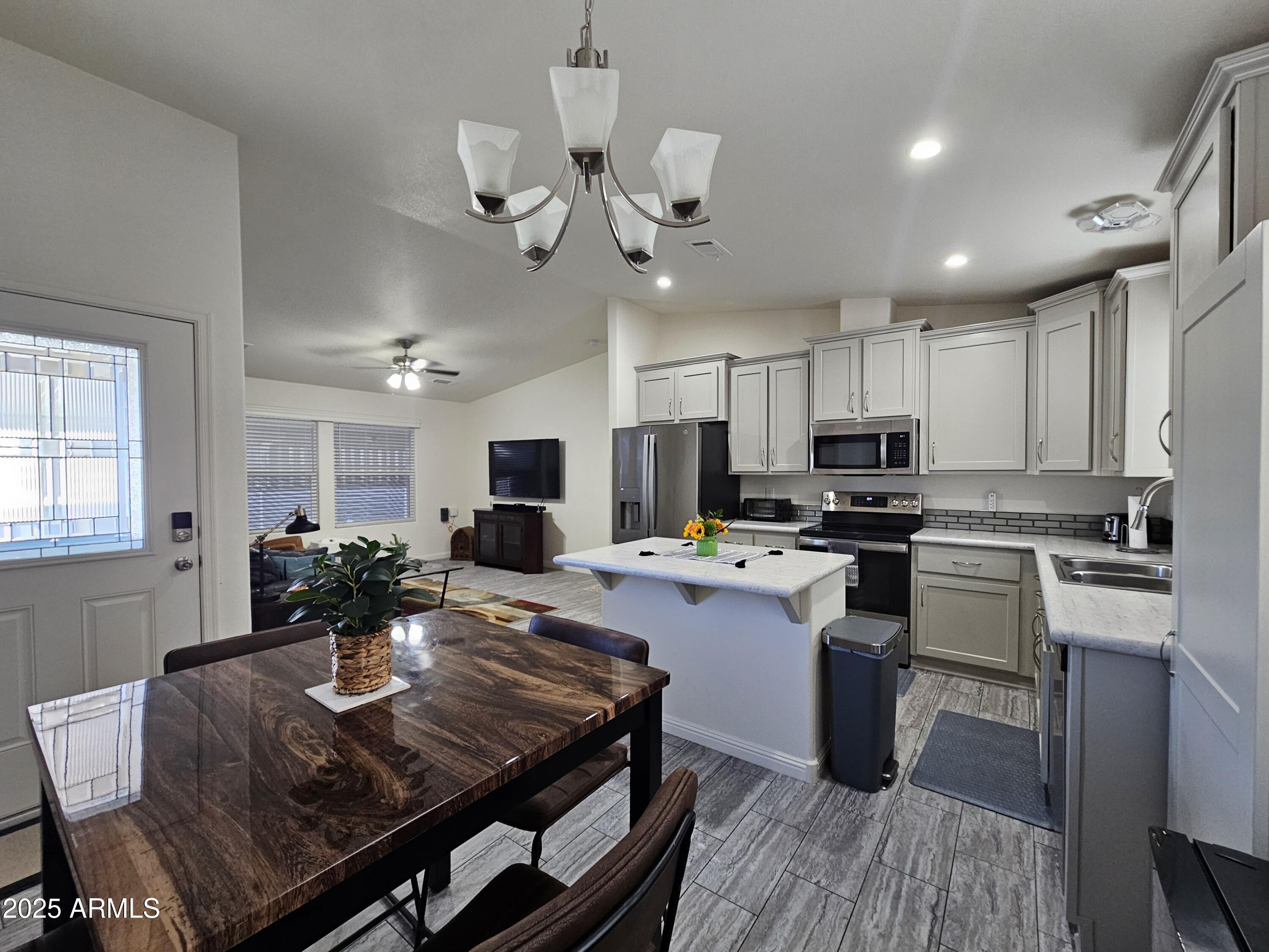 650 North Hawes Road, Unit 3124 Mesa, AZ 85207 - Photo 3 of 45 a kitchen with kitchen island a stove a table and chairs in it