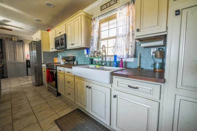 a kitchen with stainless steel appliances granite countertop a sink a stove a refrigerator cabinets and dining table