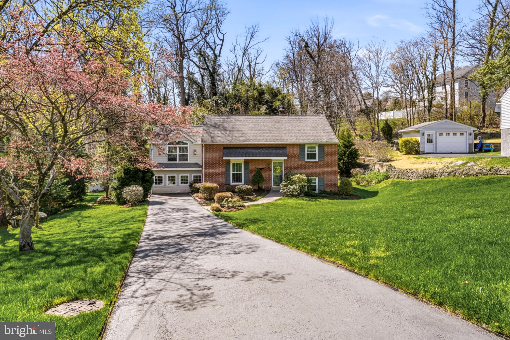 a front view of a house with a garden and trees