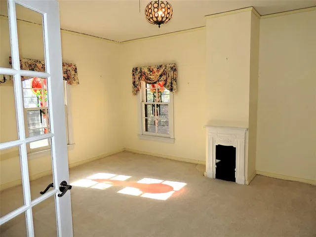 an empty room with windows and chandelier fan