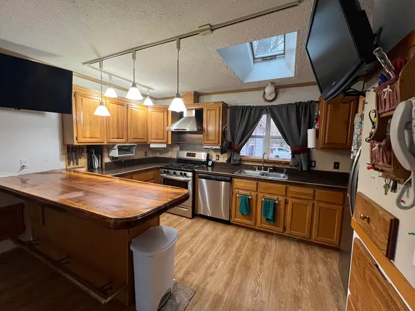 a kitchen with stainless steel appliances granite countertop a sink a stove and a wooden floors