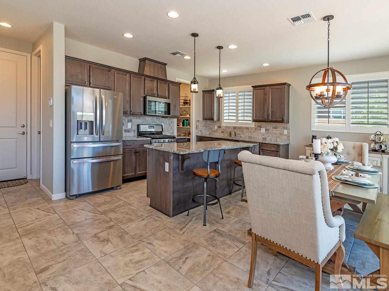 3110 Show Jumper Lane Reno, NV 89521 - Photo 6 of 28 a kitchen with stainless steel appliances granite countertop a stove top oven a refrigerator a sink dishwasher a dining table and chairs with wooden floor