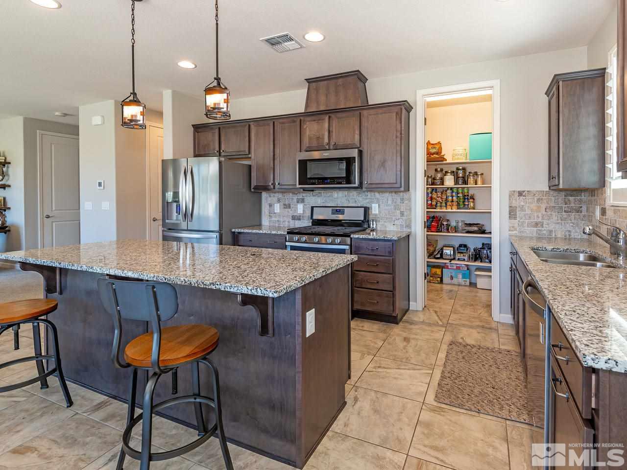 3110 Show Jumper Lane Reno, NV 89521 - Photo 8 of 28 a kitchen with stainless steel appliances granite countertop a table chairs sink and refrigerator
