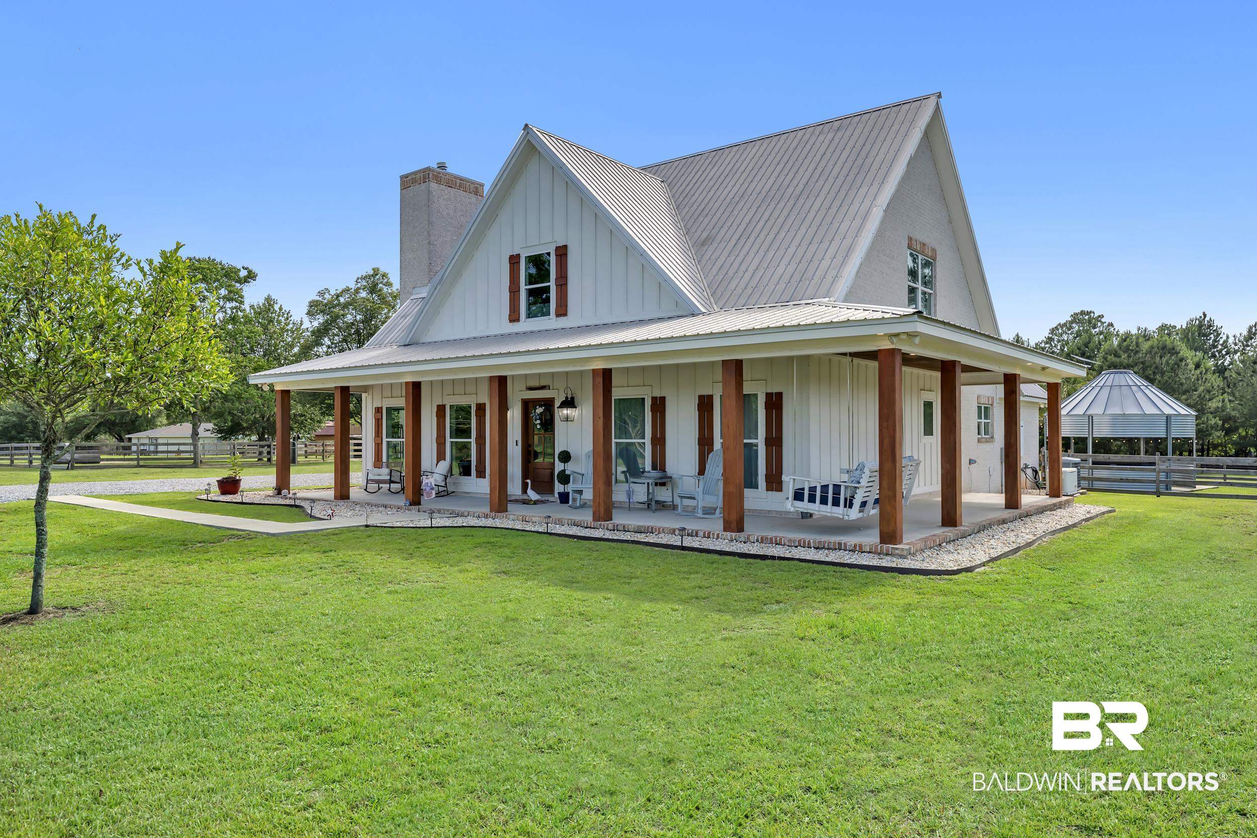 6576 Ranch Loop Road East Grand Bay, AL 36541 - Photo 2 of 39 White board-and-batten exterior with a metal roof and a full-length covered porch