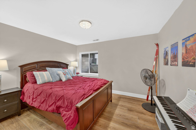 7872 Farm House Lane Midvale, UT 84047 - Photo 29 of 39 Bedroom featuring wood-finish flooring, a contemporary ceiling light fixture, and a window with white framing