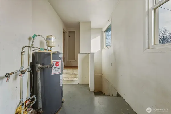 a room with water heater and wooden cabinets