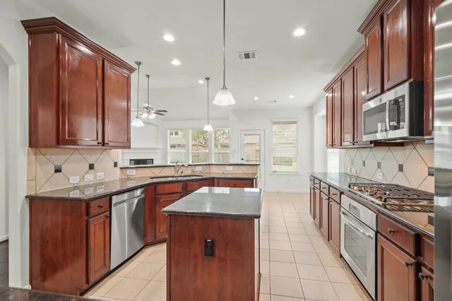 a kitchen with stainless steel appliances granite countertop a stove a sink and a microwave