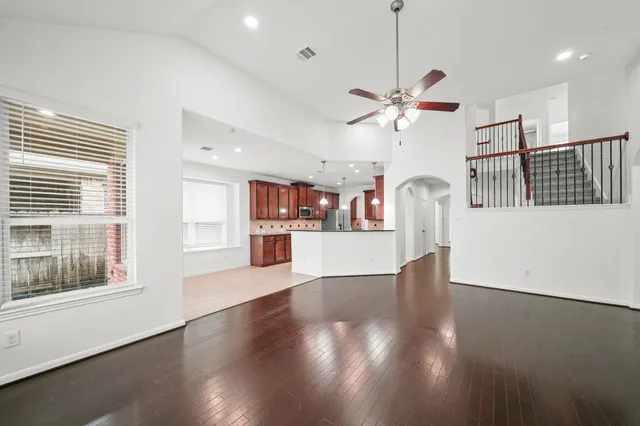 a view of a kitchen with furniture a ceiling fan and wooden floor