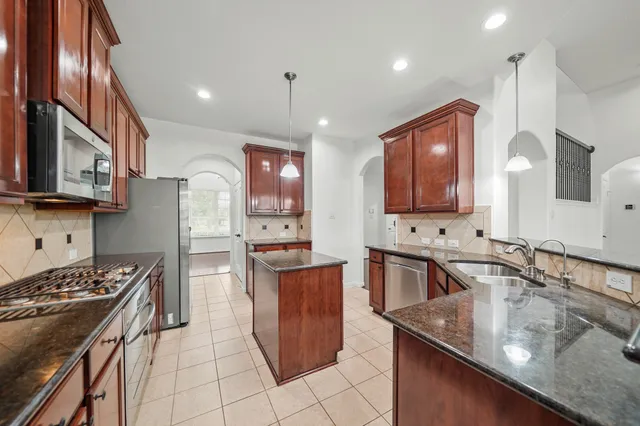 a kitchen with stainless steel appliances granite countertop a sink stove and refrigerator